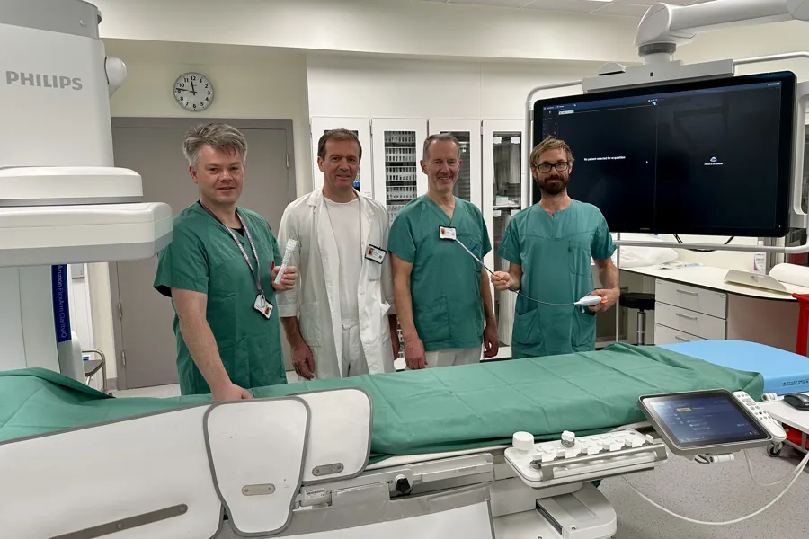 En gruppe mennesker som står ved siden av en seng