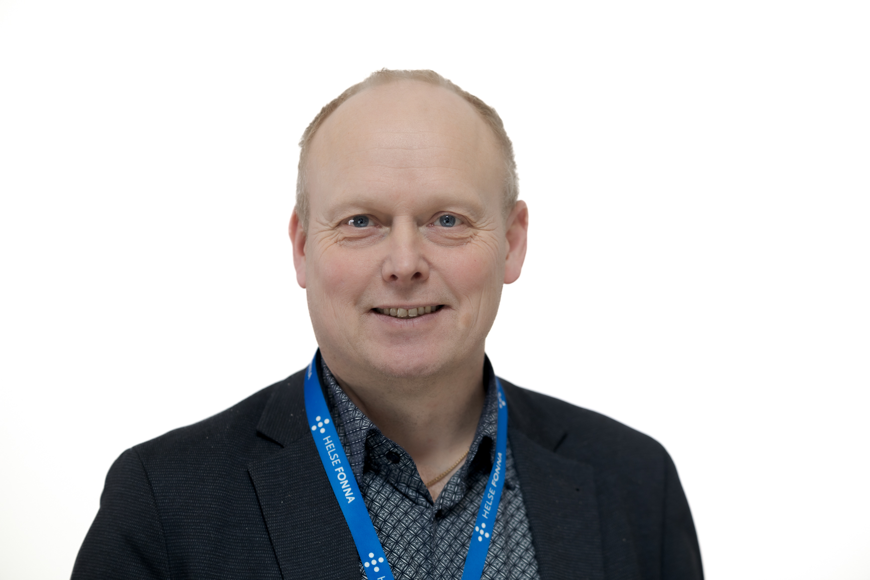 En mann iført dress og smilende