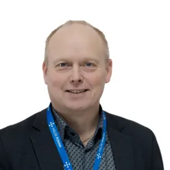 En mann iført dress og smilende