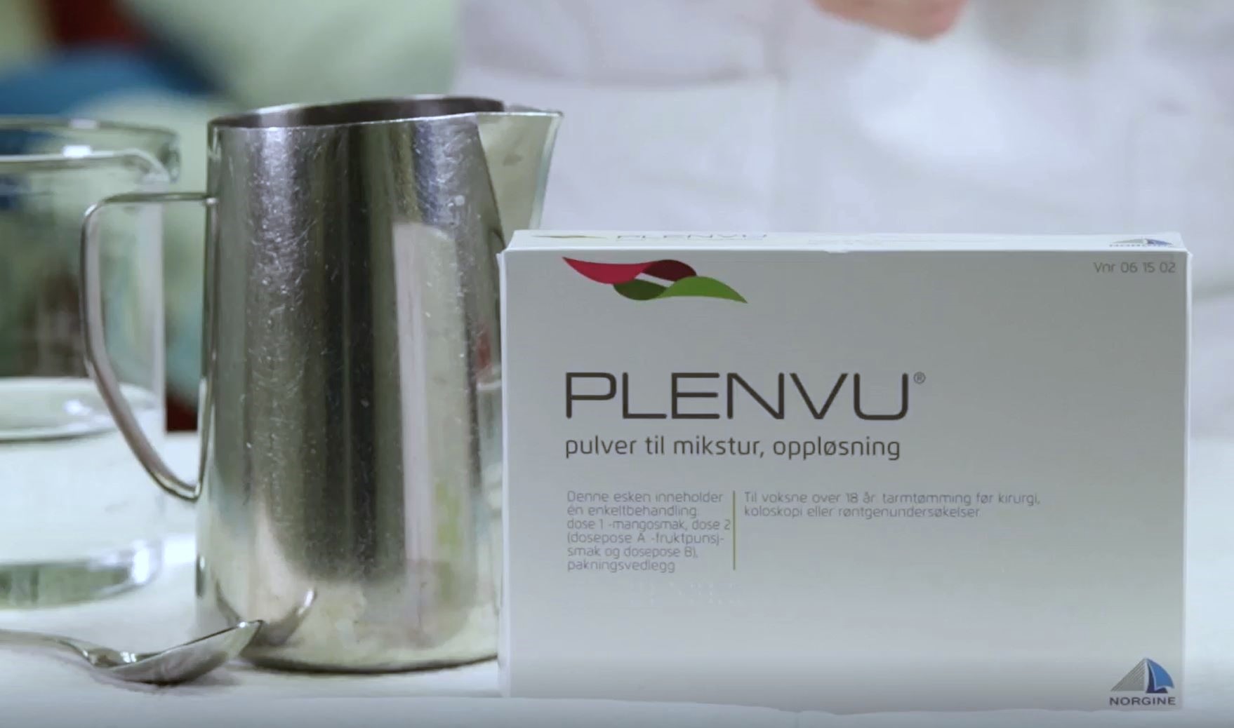 En hvit boks med en hvit etikett og et glasskrus med en brun væske i