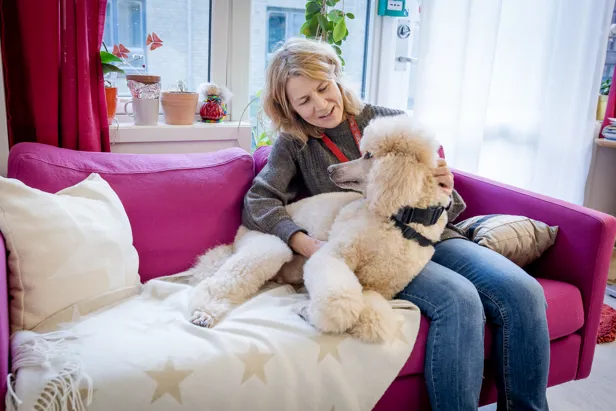 En kvinne som sitter i en sofa med en hund