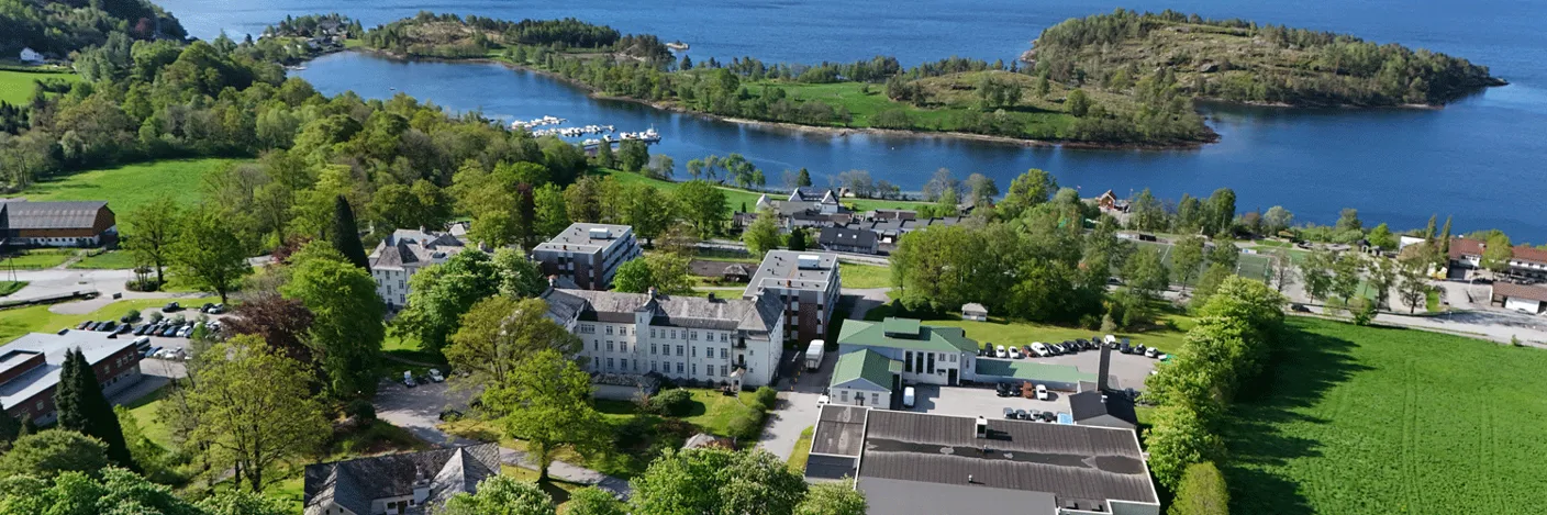 Et sjukehusområde ved sjøen med bygninger og trær rundt seg