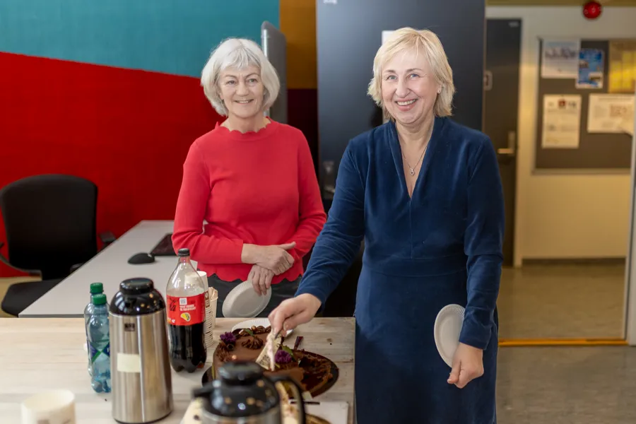 To damer står ved sida av eit bord med kaker på