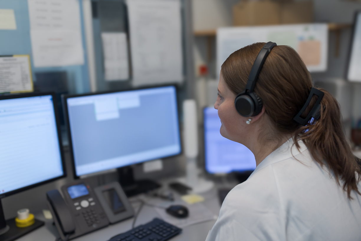 Ei kvinne med hodetelefonar som sit foran ein skjerm