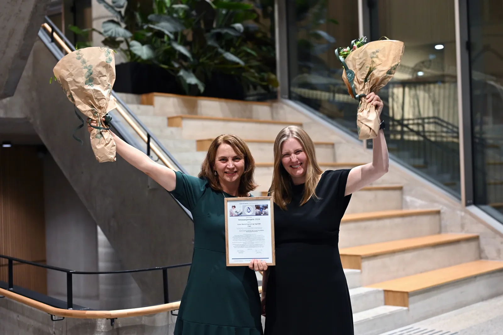 To damer som held blomsterbukettar og ein plakat