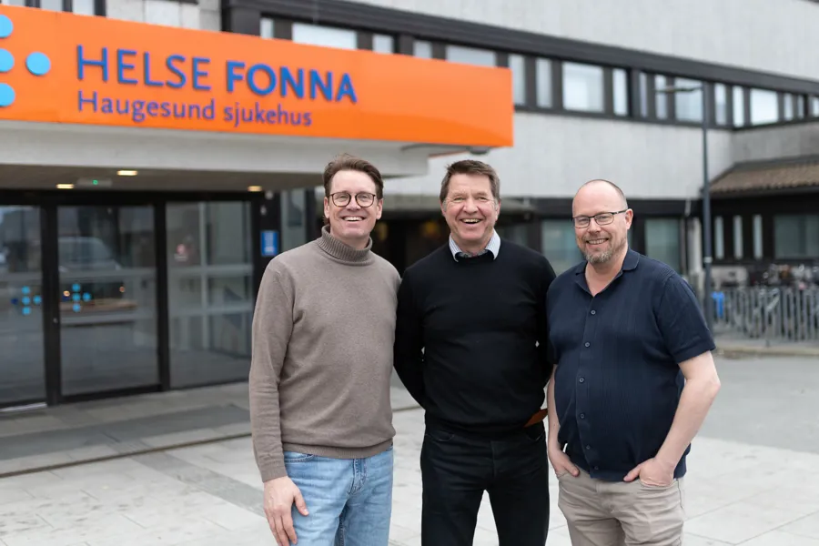 En gruppe menn poserer for et bilde foran en bygning