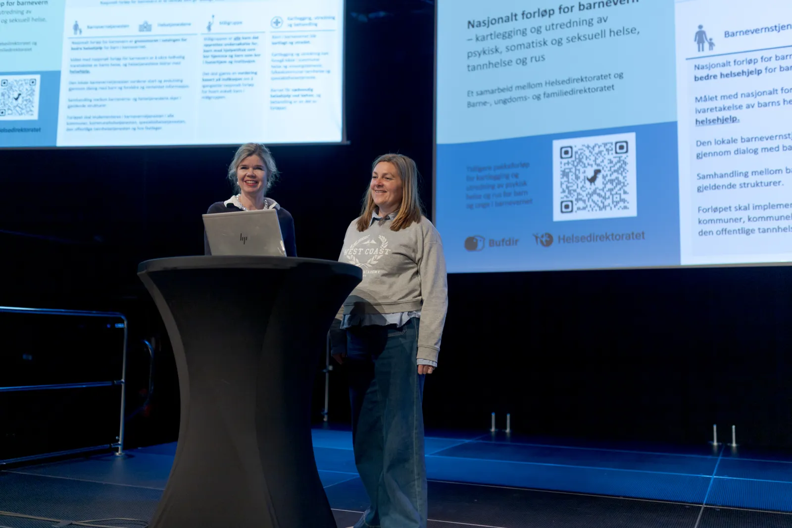 En person som står foran et podium med en person som sitter bak