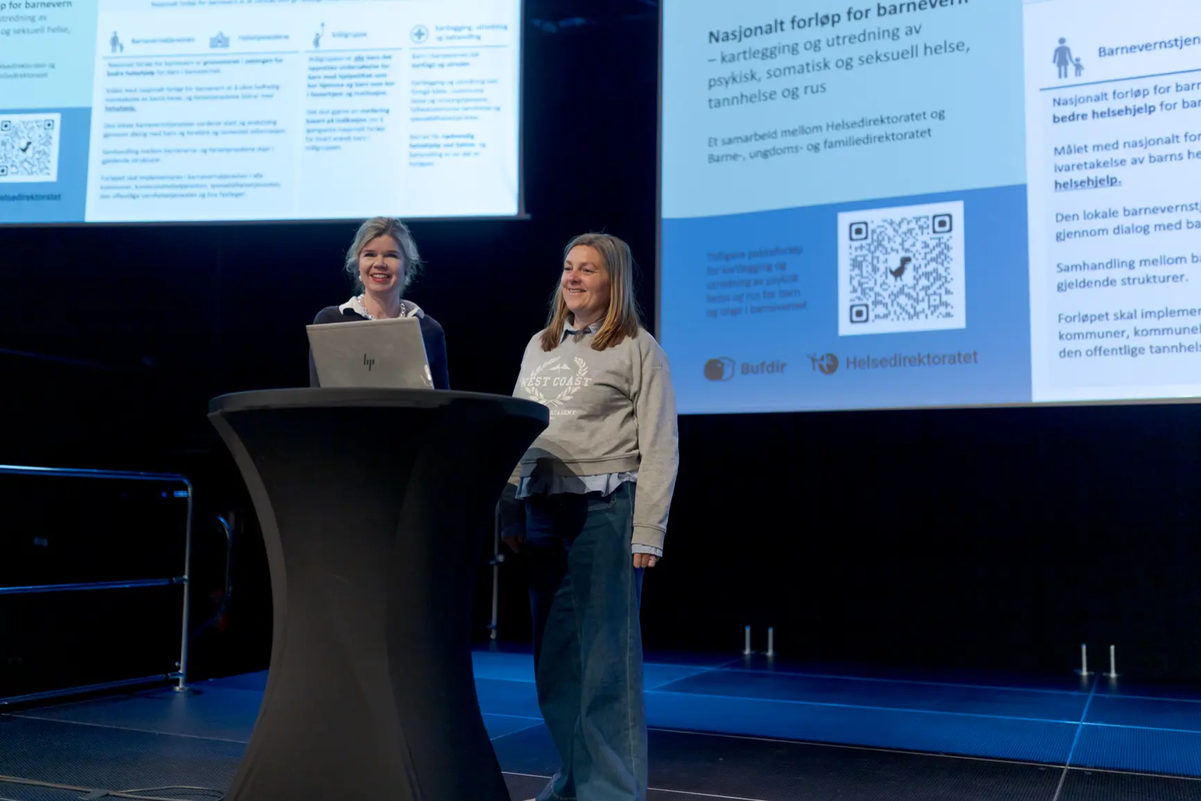 En person som står foran et podium med en person som sitter bak