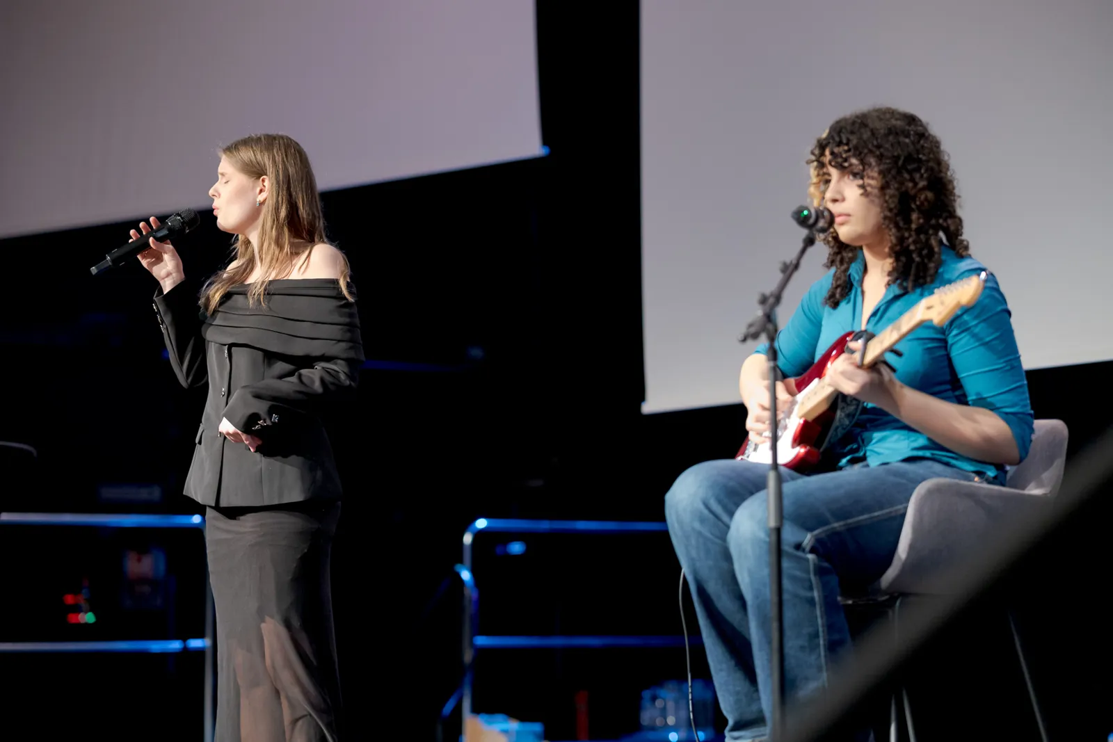 En person som synger inn i en mikrofon ved siden av en person som spiller gitar