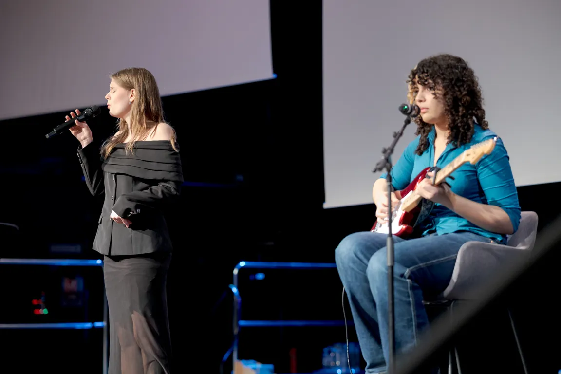 En person som synger inn i en mikrofon ved siden av en person som spiller gitar