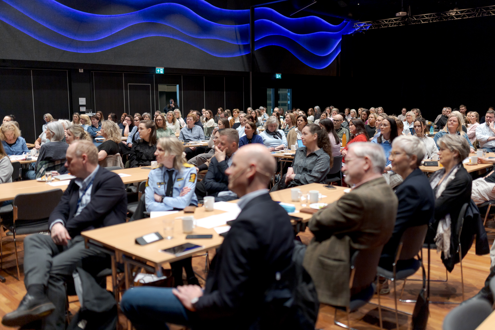 En stor gruppe mennesker som satt ved bord