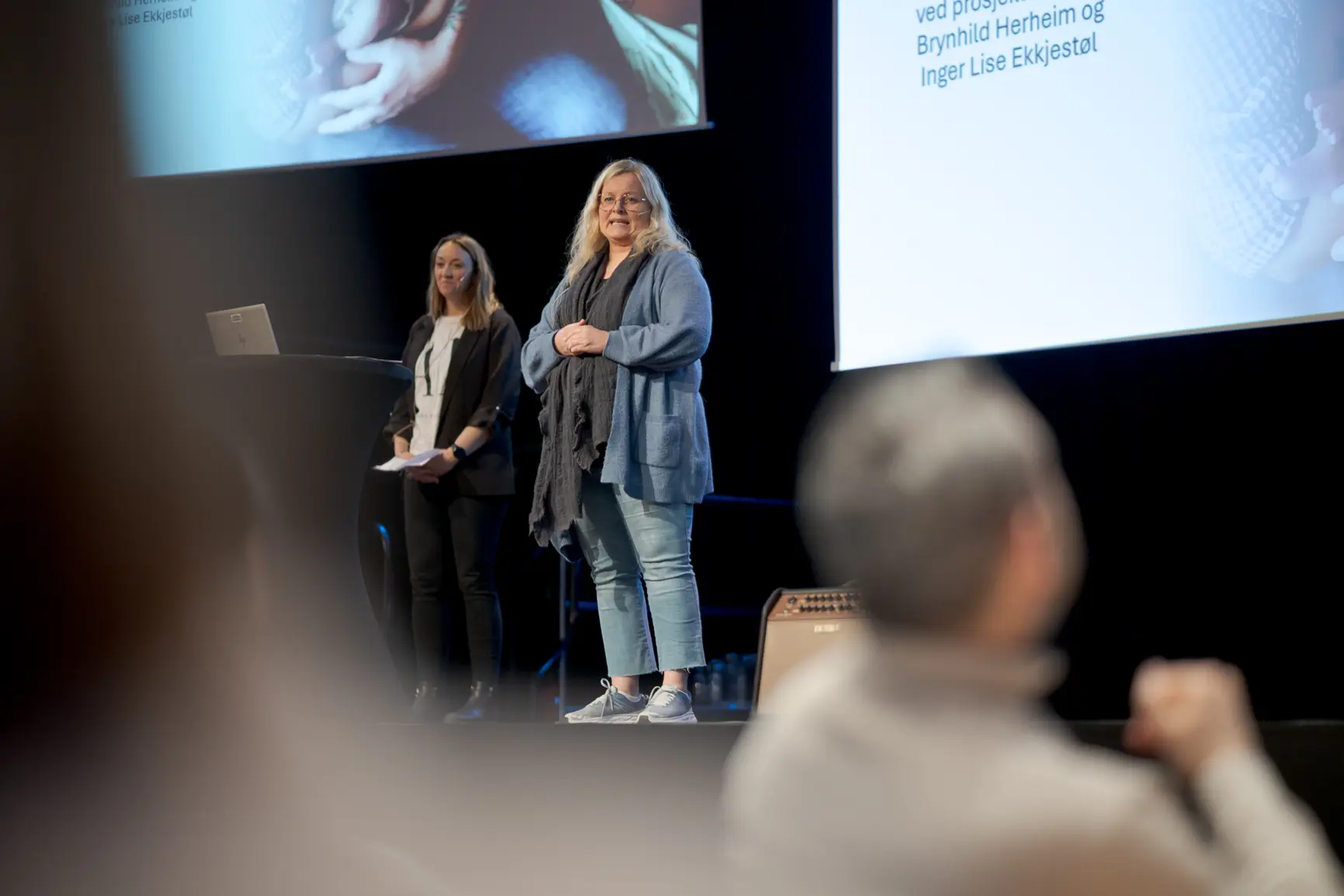 Et par kvinner som står foran en projektorskjerm