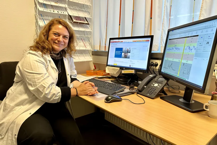 En person som sitter ved et skrivebord med en datamaskin og en telefon