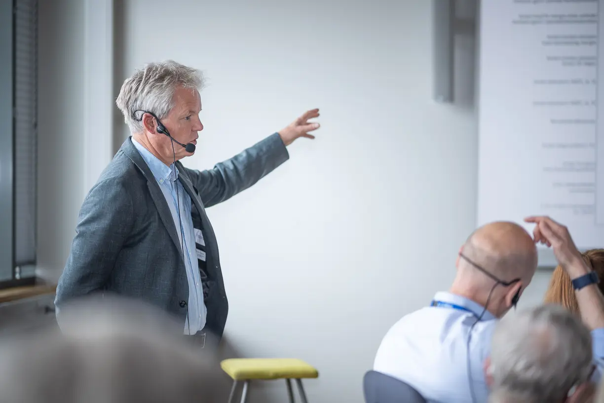 En mann i dress som peker på en tavle