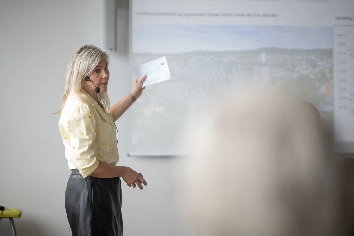 En person som holder et papir og ser på en tavle