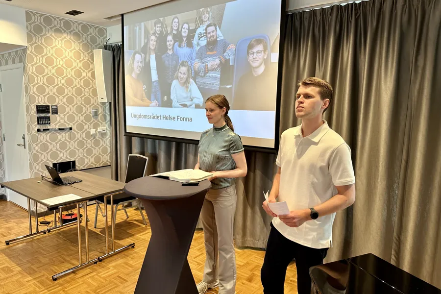 En mann og en kvinne som står foran en projektorskjerm