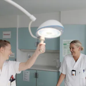 En person i hvit laboratoriefrakk som holder en lyspære