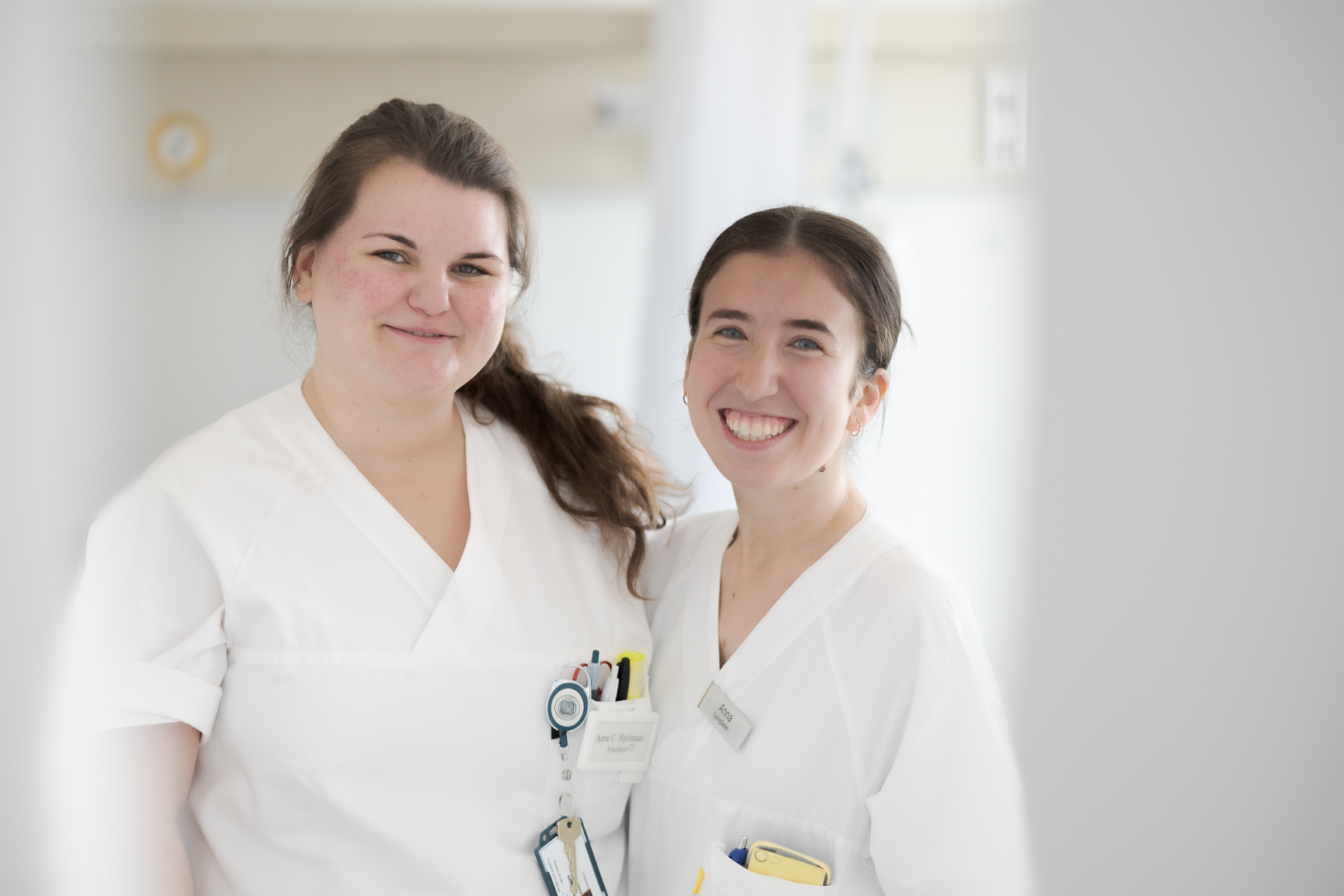 Et par kvinner iført hvite laboratoriefrakker og merker