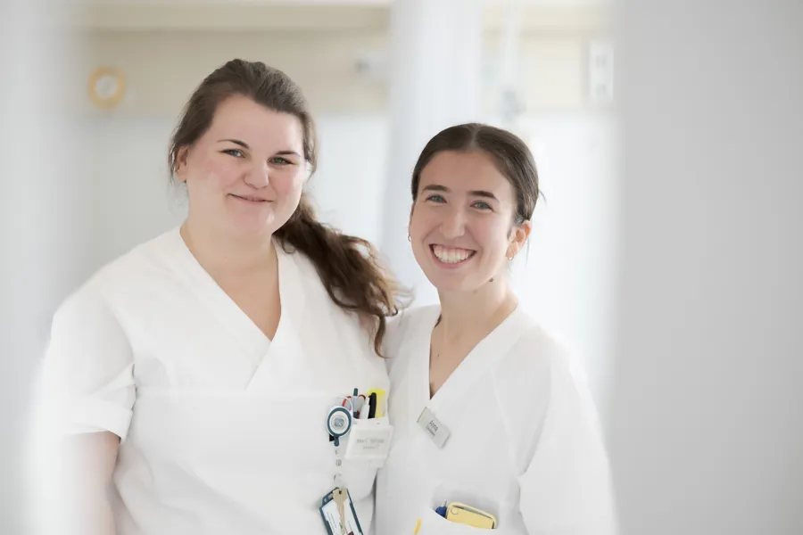 Et par kvinner iført hvite laboratoriefrakker og merker