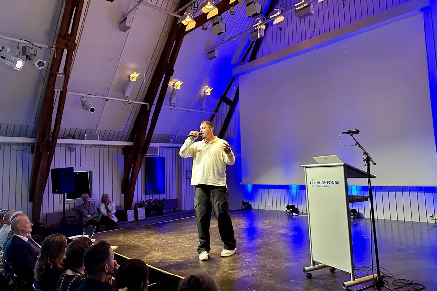En person på en scene med en mikrofon foran en folkemengde