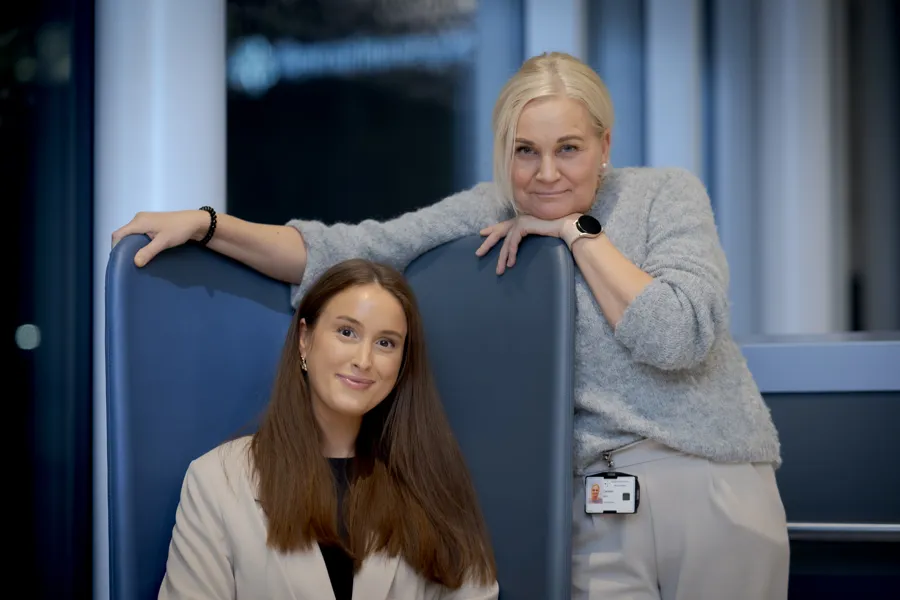 En dame sitter i en stol og en annen dame står bak stolen