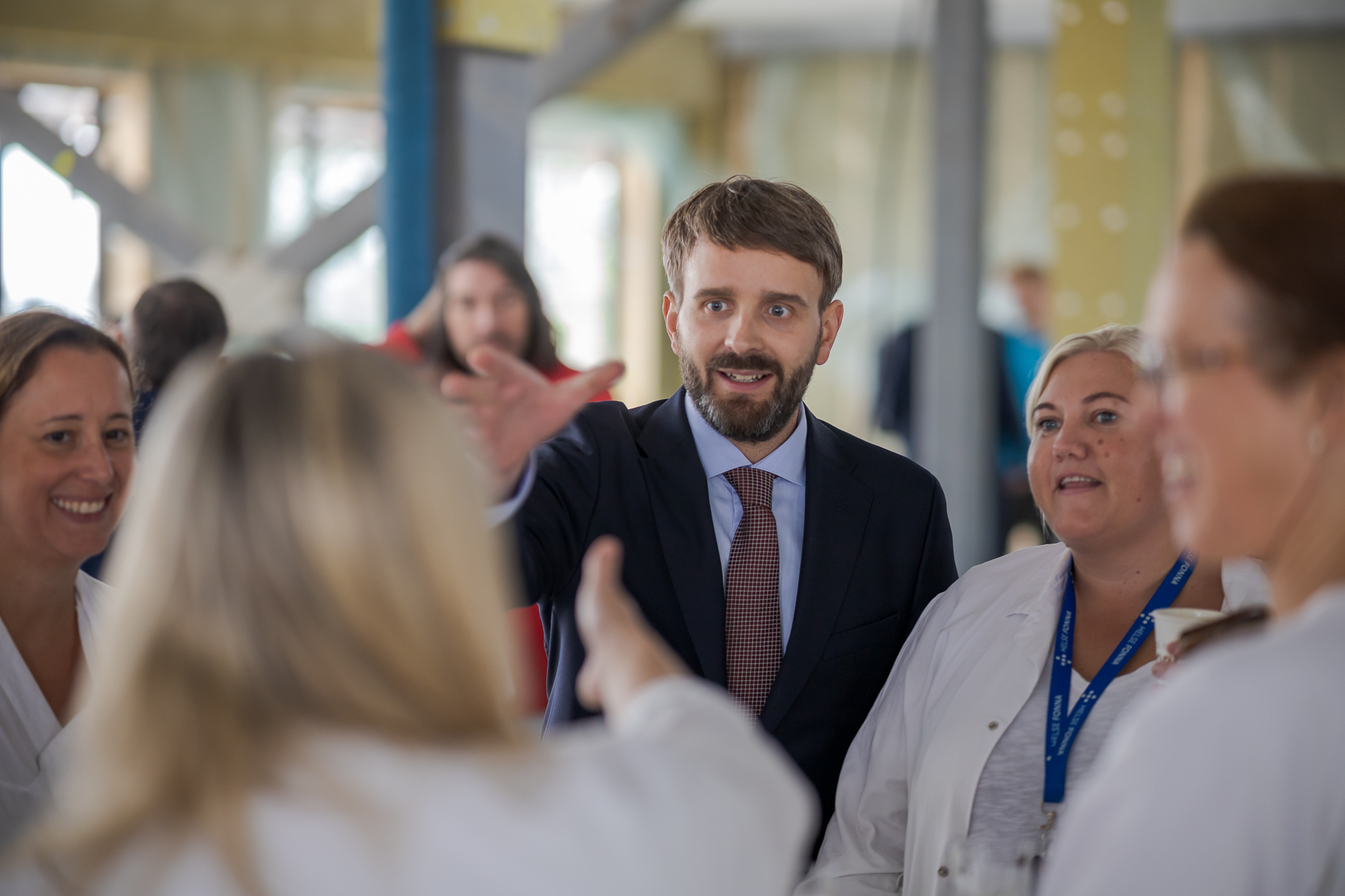 En person i dress og slips som snakker med en gruppe mennesker