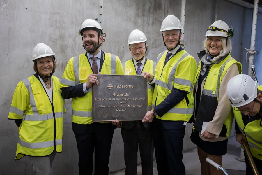 En gruppe mennesker iført sikkerhetsvester som holder et skilt