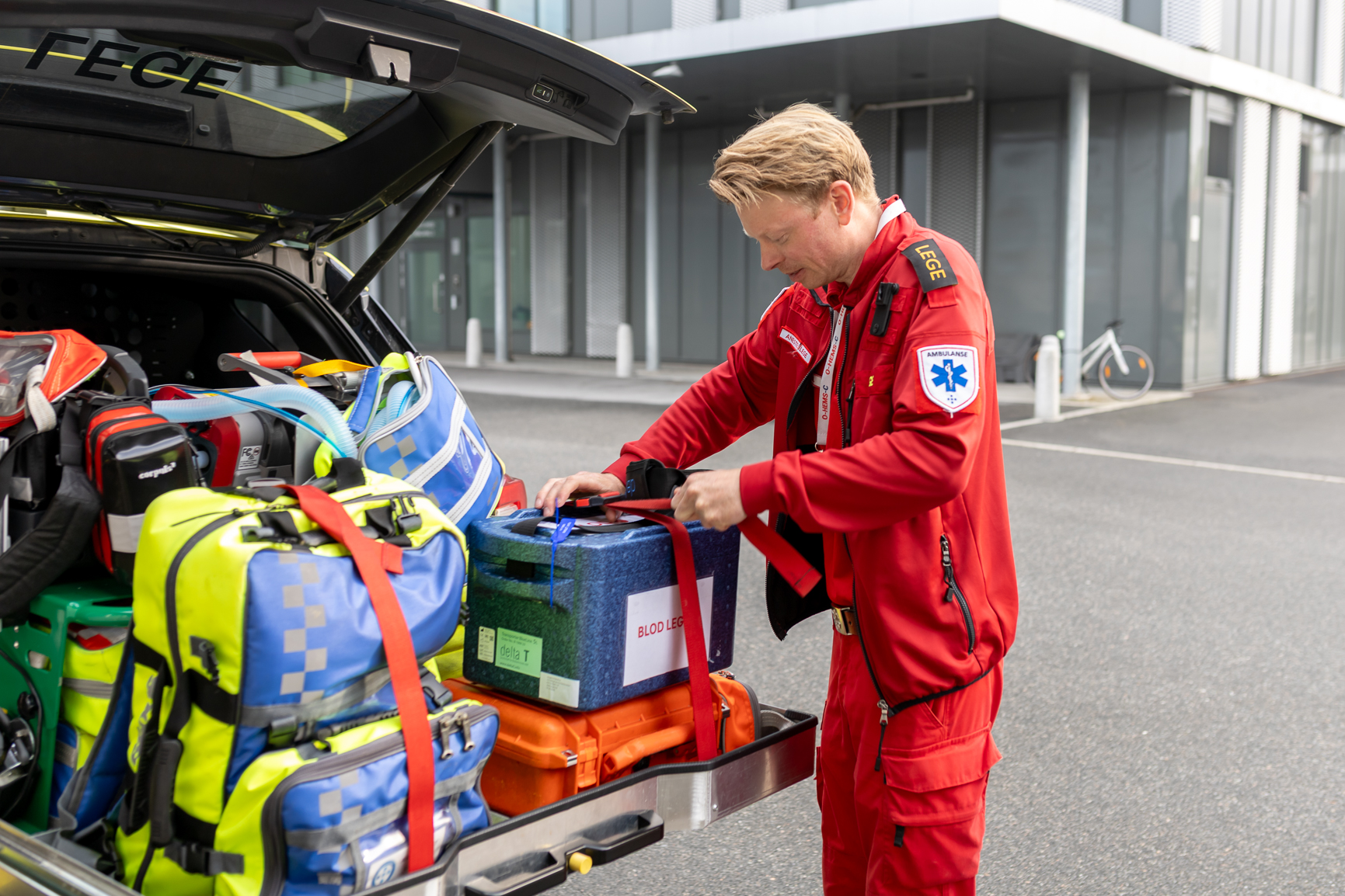 En mann i rød dress som skyver en vogn full av bagasje