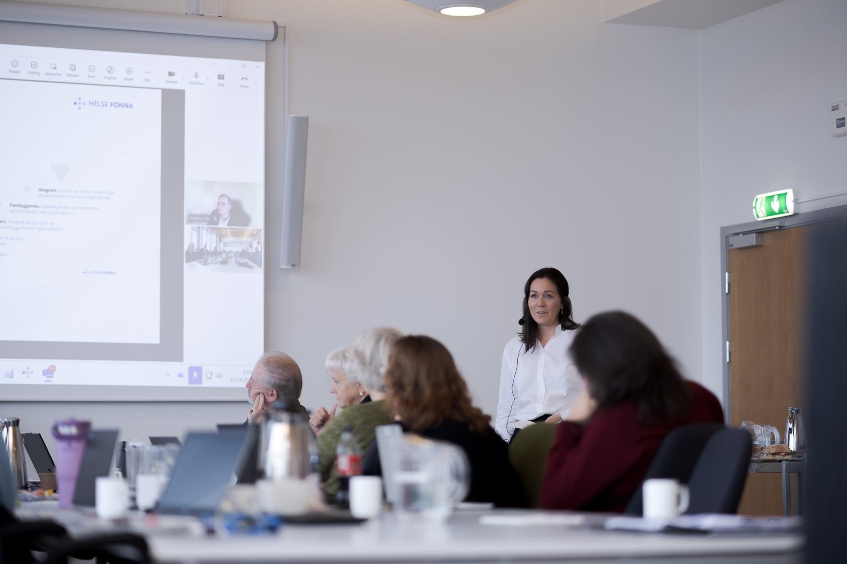 En gruppe mennesker som sitter ved et bord med en projektorskjerm
