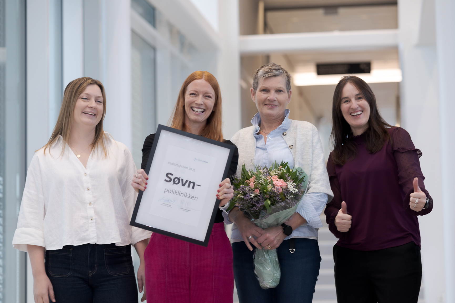 En gruppe kvinner som holder blomster og et skilt