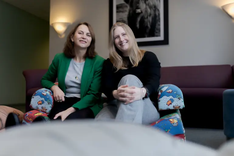 Et par kvinner som sitter på en sofa